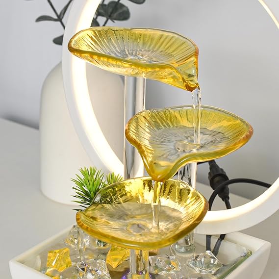 Yellow glass tiered fountain with crystals on a white surface