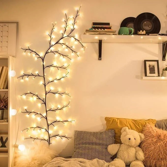 Decorative wall light with branches and lights in a cozy room with a teddy bear and pillows.
