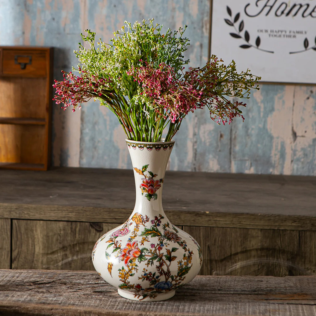 Decorative vase with floral design on a wooden surface, with a rustic background.
